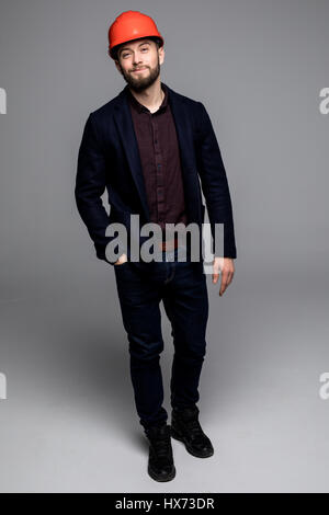 Mann in einem schwarzen Anzug und Bau Helm Blick zur Seite und halten schwarze Ordner auf grauem Hintergrund Stockfoto