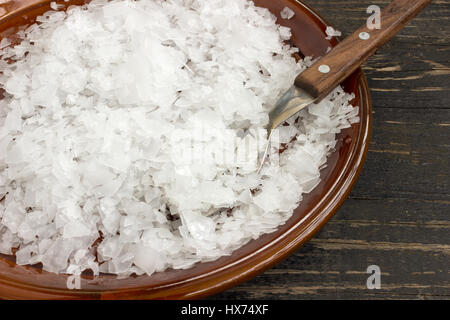 Magnesium-Chlorid-Flocken, volle Untertasse und Löffel Stockfoto