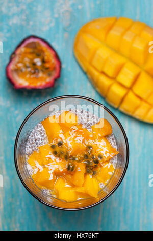 Gesundes Frühstück. Chia Pudding mit Mango im Glas Gläser, Mango Hälften, Passionsfrucht/Maracuja auf einem blauen Hintergrund aus Holz. (Ansicht von oben) Stockfoto