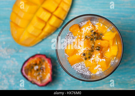 Gesundes Frühstück. Chia Pudding mit Mango im Glas Gläser, Mango Hälften, Passionsfrucht/Maracuja auf einem blauen Hintergrund aus Holz. (Ansicht von oben) Stockfoto