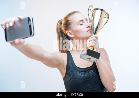 junge Frau mit geschlossenen Augen machen Selfie auf Smartphone Trophäe mit gedrückter Stockfoto