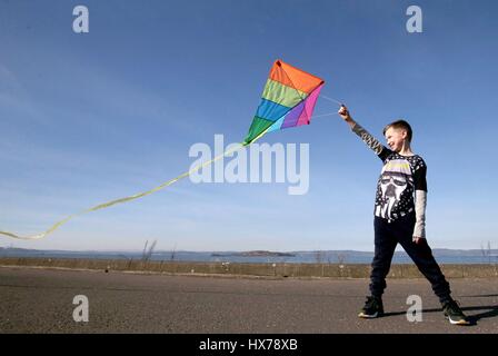 Anmerkung des Herausgebers: elterliche Erlaubnis Kyle Osborne, 9, spielt mit seinem Kite in der Sonne entlang der Silverknowes-Promenade in Edinburgh. Stockfoto