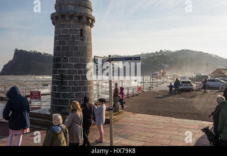 Teignmouth Leuchtturm und Leute zu beobachten eine Flut verursachen Gischt von den Wellen schlagen die Ufermauer. Stockfoto