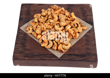 Eine Handvoll geröstete Cashewnüsse gewürzt auf dunklem Rot Holz die Portion Board, isoliert auf weißem Hintergrund. Stockfoto