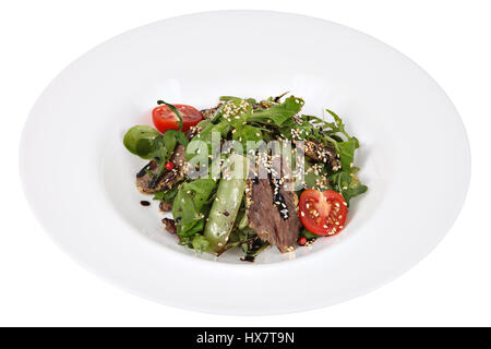 Salat mit Rucola und dünn geschnittenes Rindfleisch auf weißen runden Teller, isoliert auf weißem Hintergrund. Stockfoto