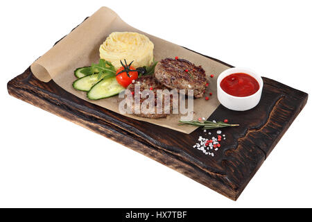 Zwei Kalbsschnitzel mit Garnierung auf dunklen braunen Portion Brett, isoliert auf weißem Hintergrund. Stockfoto