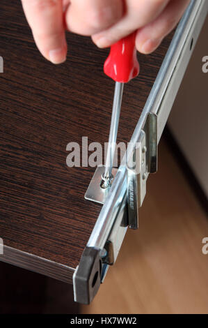 Möbel Montage, Einbau Laufstrecken, Schublade Folie hintere Halterung, mit einem manuellen Schraubendreher Befestigungsschraube passend. Stockfoto