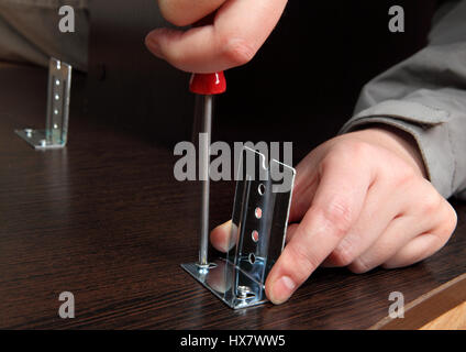 Möbelmontage von Hand, Nahaufnahme, Schraubendreher, Schrauben die Schraube Befestigung Metallbügel auf der Folie Schienen Tastatur Tablett-Computer-Schreibtisch. Stockfoto