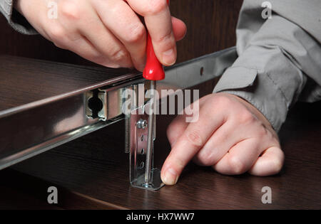 Montage von Möbeln, Installation Computer Schreibtisch Tastaturunterlage verfolgen Schublade Diaschiene, manuelle Schraubenzieher Schraube einschrauben. Stockfoto