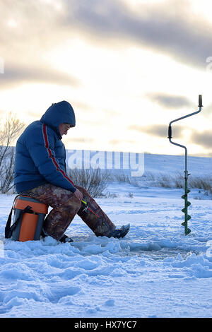 älterer Mann Angeln im Winter auf dem See Stockfoto