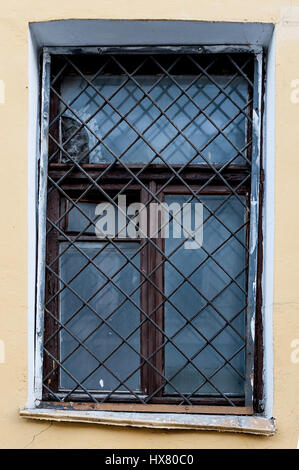 Alte Fenster mit eine rostige Gitter auf einer alten Mauer mit Steinen Stockfoto