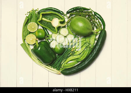 Grünes Gemüse mit Herzform auf hölzernen Hintergrund. Stockfoto