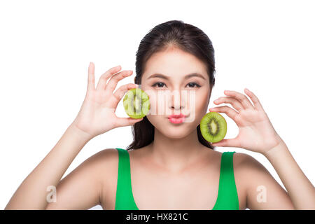 Tropische Früchte. Gesunde Ernährung. Charmante junge Asiatin halten frische saftige Kiwi und lächelt. Grünen Hintergrund. Stockfoto