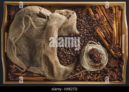 Leinenbeutel mit Kaffeekörner, Hank eine Schnur, ein Stick von Zimt, Wacholder-Beere und Früchte von einem Anisetree auf einem Tablett aus einem Bambus Stockfoto