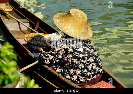 Amphawa, Thailand - 17. Dezember 2010: Thai Frau trägt einen Strohhut sitzt in ihrem Boot verkaufen Fischbällchen an den schwimmenden Markt Amphawa Stockfoto