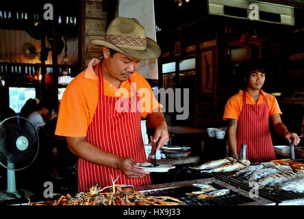 Amphawa, Thailand - 17. Dezember 2010: Thai Chef Cowboy Hut Grillen Meeresfrüchte in seinem Restaurant Kai auf dem schwimmenden Markt Amphawa Stockfoto