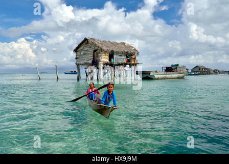 SEMPORNA SABAH, MALAYSIA - 19. April 2015: Bajau Laut Kinder Paddel Boote in der Nähe von gestelzt Häuser in der Celebes familienfreundlichen Bajau Laut sind nomadische Meer g Stockfoto