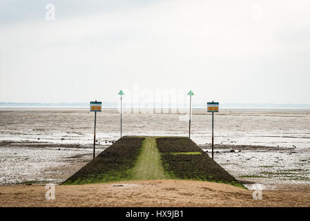 Essex Strand mit Sand führen auf auf eine Algen bedeckt Steg oder Rutschen Weg, der an eine Mudbank mit dem Meer am Horizont hält. Stockfoto