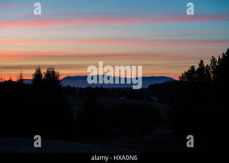 Die Sonne geht hinter Ben Wyvis in den schottischen Highlands, in der Nähe von Inverness am ersten Tag der Britische Sommerzeit und einen anderen Tag der herrlichen Sonnenschein und blauem Himmel in den Highlands. Stockfoto