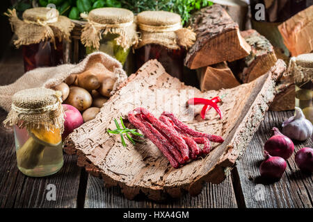 Hausgemachte dünne Würste in Speisekammer auf alten Holztisch Stockfoto