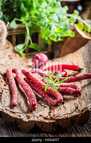 Frische dünne Würste in Speisekammer auf Rinde Stockfoto