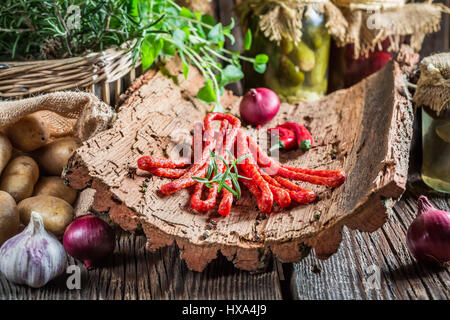 Geräucherte dünne Würste in ländlichen Lagerraum auf Rinde Stockfoto