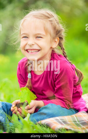 Kleines Mädchen, kleine grüne Pflanze in ihren Händen hält Stockfoto