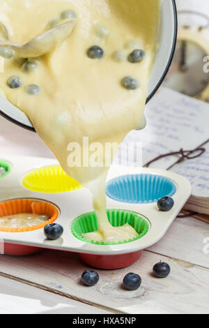 Vorbereitung für leckere Muffins mit Heidelbeeren auf alten weißen Tisch Stockfoto