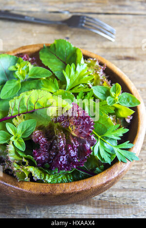 Frische Bio grüner gemischter Salat Blätter über rustikalen hölzernen Hintergrund - biologisch gesunde vegane vegetarische Ernährung Detox Lebensmittelzutat Stockfoto