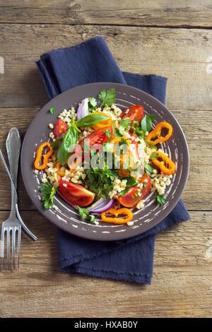 Tomaten-Couscous-Salat mit Gemüse und grünen - gesunde vegetarische vegane Gemüse Bio Diät Salat essen über rustikalen Holztisch mit Kopie s Stockfoto