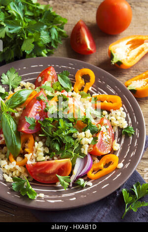 Tomaten-Couscous-Salat mit Gemüse und grünen - gesunde vegetarische vegane Gemüse Bio Diät Salat essen über rustikalen Holztisch mit Kopie s Stockfoto