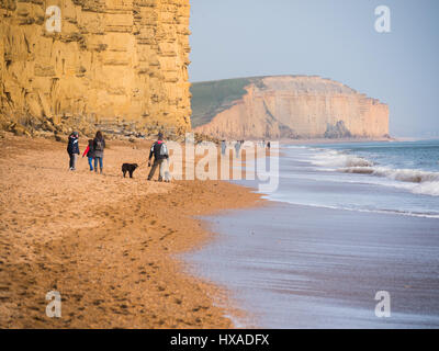 Die Menschen die Sonne zu genießen, wie die Wolke schließlich löscht und eine trübe, aber sonniger Nachmittag folgt. Mit einem Wetter hoch folgen und wärmere Temperaturen erwartet an diesem Wochenende. Burton Bradstock, Dorset, Großbritannien Stockfoto