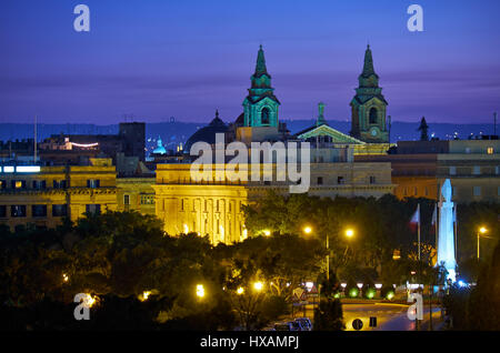 Nachtansicht der Kirche von St. Publius mit dem Kriegerdenkmal in Floriana aus der Upper Barrakka Gardens in Valletta Stockfoto