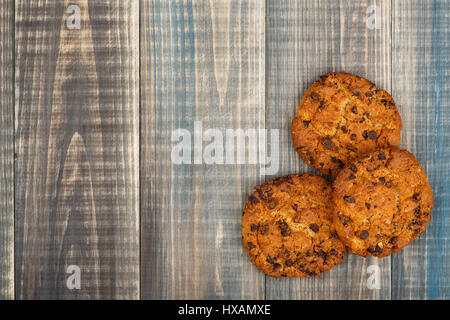 Haferflocken-Cookies mit Schokolade-Chips liegen auf einem hölzernen Hintergrund. Es ist ein Ort für Text auf der linken Seite. Stockfoto