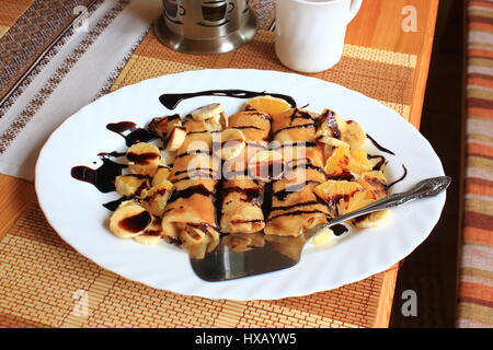 Pfannkuchen gefüllt mit Grieß, Bananen und Orangen getränkt dunklen Schokolade Stockfoto