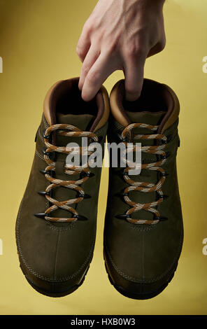 Wandern Schuhe hängen einerseits isoliert auf gelbem Hintergrund. Nahaufnahme von paar moderne aktiv Wandern Schuhe Stockfoto