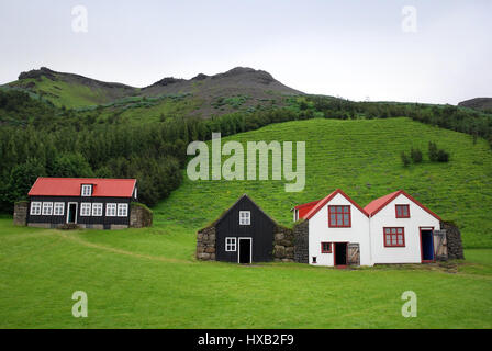 Die malerische Aussicht auf die alte weiß und schwarz bemalten Häusern im Nationalmuseum in Skógar, Island, dahinter die grünen Gebirge Eyjafjöll Stockfoto