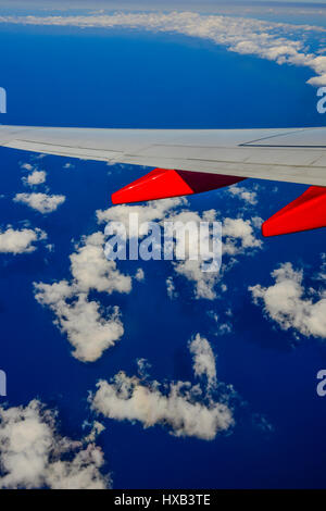 Eine Tragfläche im Vordergrund mit weißen Wolken und blauer Himmel gesehen vom Fenster des kommerziellen airliner Stockfoto