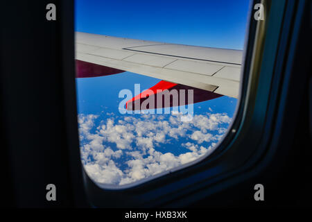 Eine Tragfläche im Vordergrund mit dramatischen weiße Wolken und blauer Himmel gesehen vom Fenster des kommerziellen airliner Stockfoto