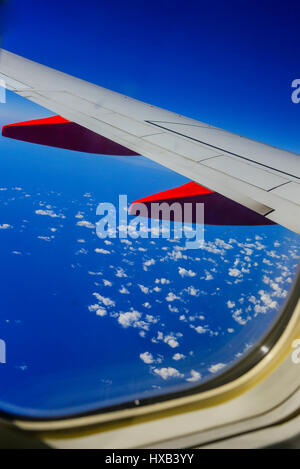 Eine Tragfläche im Vordergrund mit dramatischen weiße Wolken und blauer Himmel gesehen vom Fenster des kommerziellen airliner Stockfoto