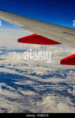 Eine Tragfläche im Vordergrund mit dramatischen weiße Wolken und blauer Himmel gesehen vom Fenster des kommerziellen airliner Stockfoto