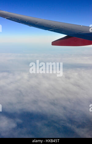 Eine Tragfläche im Vordergrund mit dramatischen weiße Wolken und blauer Himmel gesehen vom Fenster des kommerziellen airliner Stockfoto