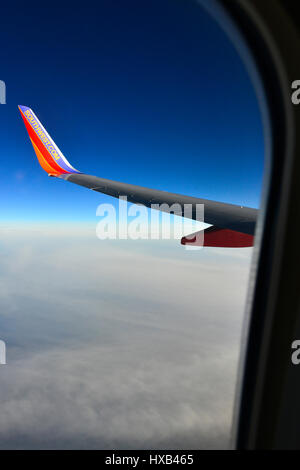 Eine Tragfläche im Vordergrund mit dramatischen weiße Wolken und blauer Himmel gesehen vom Fenster des kommerziellen airliner Stockfoto