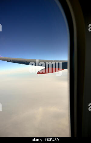 Eine Tragfläche im Vordergrund mit dramatischen weiße Wolken und blauer Himmel gesehen vom Fenster des kommerziellen airliner Stockfoto