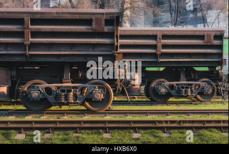 Güterwagen auf den Bahnhof und Zug gegen metallurgische Fabrik bei Sonnenuntergang. Sicht der Industrie. Close-up. Eisenbahn in den Abend. Eisenbahn-pla Stockfoto