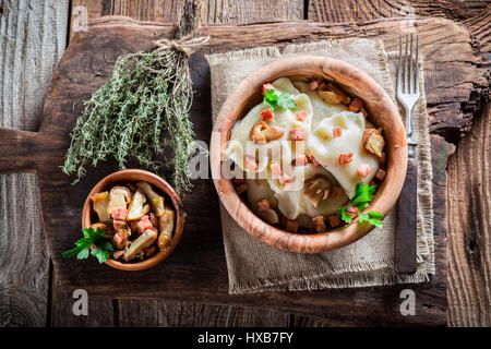 Hausgemachte Teigtaschen mit Mushrroms auf alten Holztisch Stockfoto