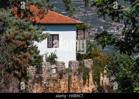 Altes Steinhaus, weiß lackiert mit rotem Ziegeldach hinter Burgmauern von Alanya mit Blick über Taurusgebirge Stockfoto