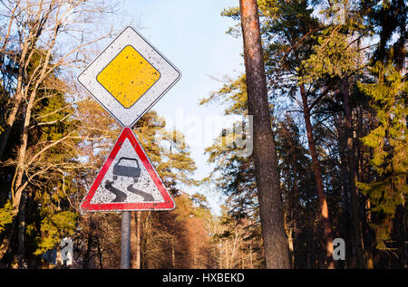 Verschmutzt Verkehrsschild rutschige Straße in den Wald, vorsichtiges Fahren auf dem Land reisen. Stockfoto