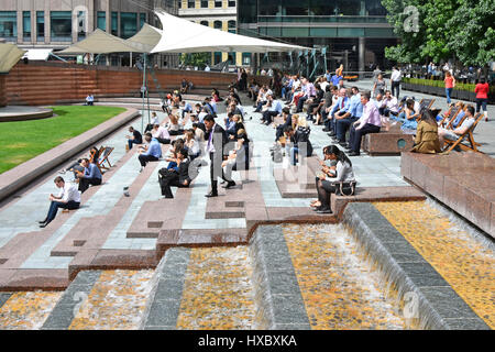 London Frauen Männer weibliche und männliche Büro Arbeiter Arbeiter uk Mittagspause Entspannung im Sonnenschein im Sommer Saison viele Snacks Essen neben Brunnen Wasserspiel Stockfoto