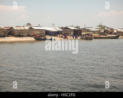 Ngamba Island, Uganda - 20. Februar 2017: Dorfbewohner mit Booten am Ufer des Ngamba Island im Lake Victoria, Uganda außerhalb Holzhäuser. Stockfoto